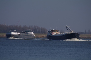 Snelle en langzame vrachtboot in de bocht van de Oude Maas