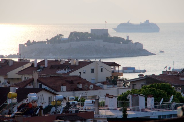 Blik vanaf ons dakterras bij laaghangende zon. Een cruiseschip kiest de route tussen Turkije en het Griekse eiland Samos.